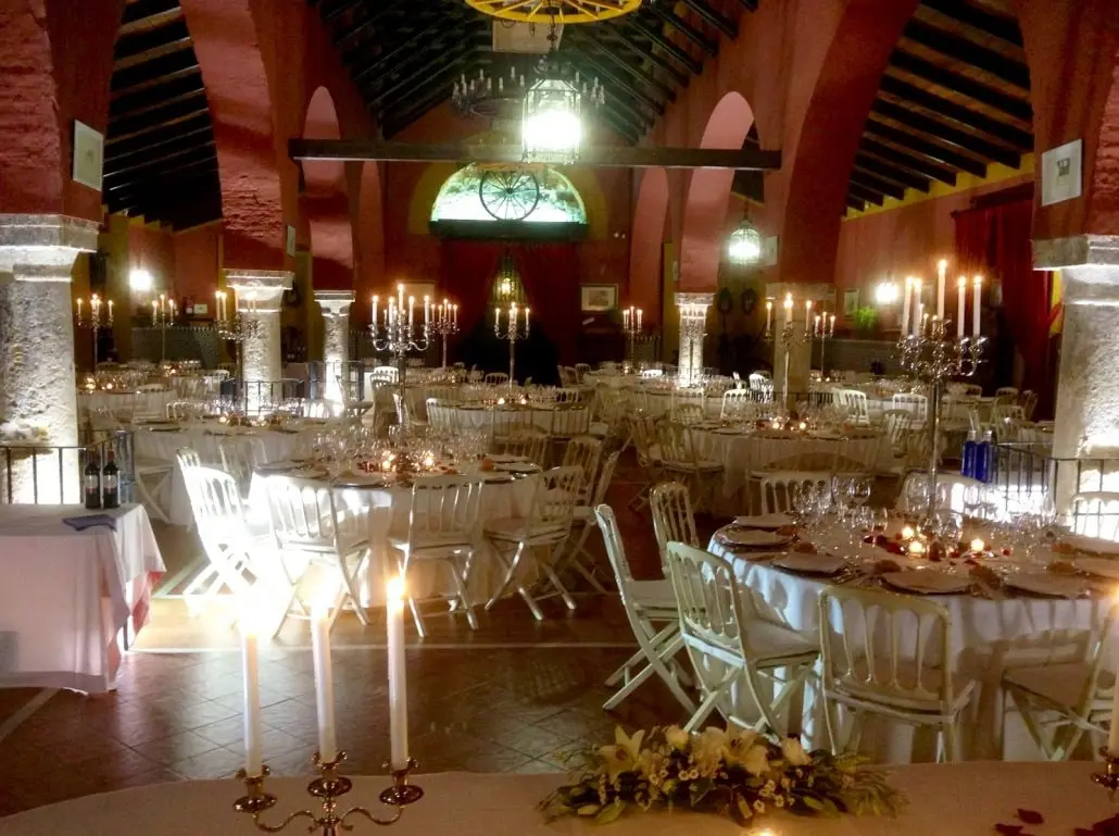 Mesas redondas con candelabros encendidos bajo arcos de ladrillo